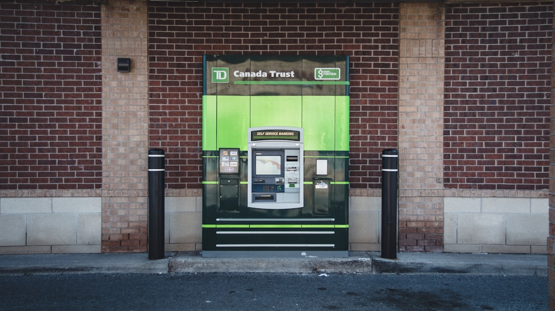 a green and black atm machine in front of a brick building