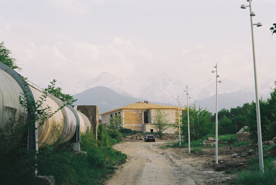 Rural road leading to a building with mountains behind