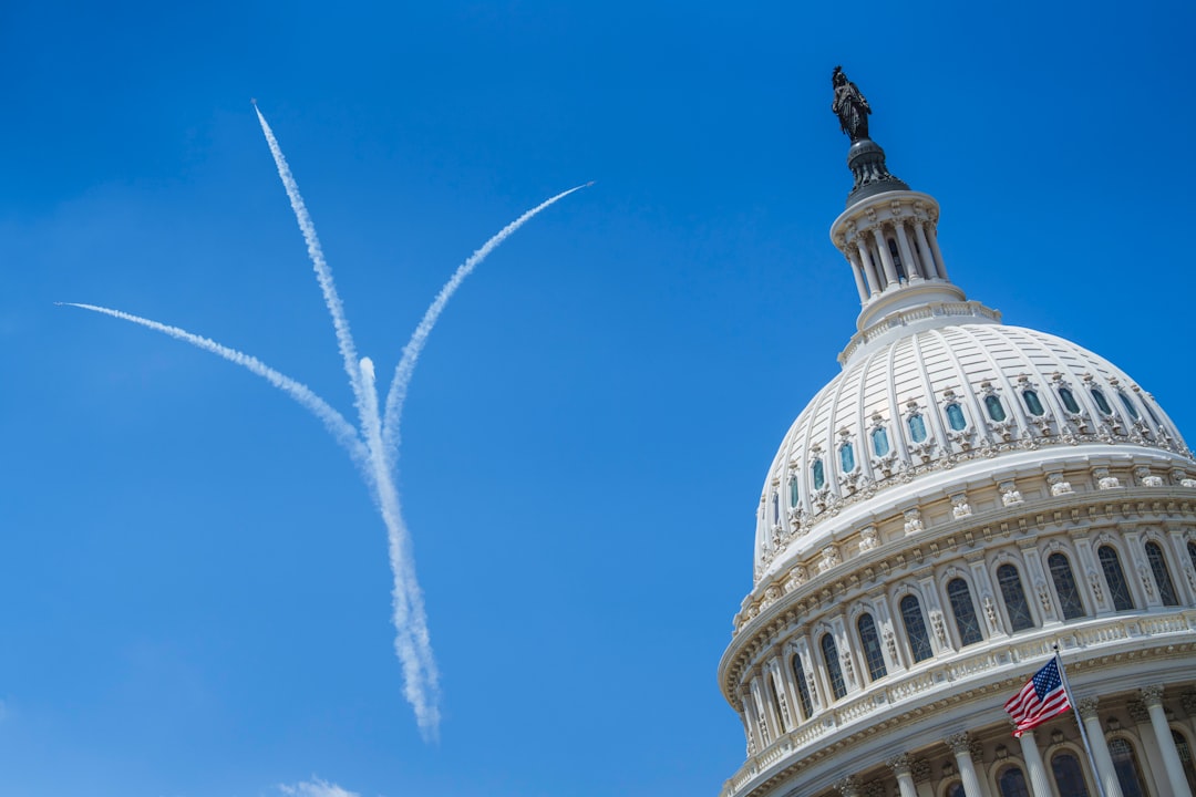 U.s. capitol building and three airplane contrails in blue sky.