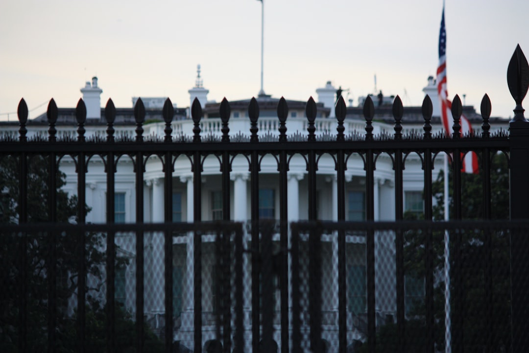 The white house behind a dark metal fence.