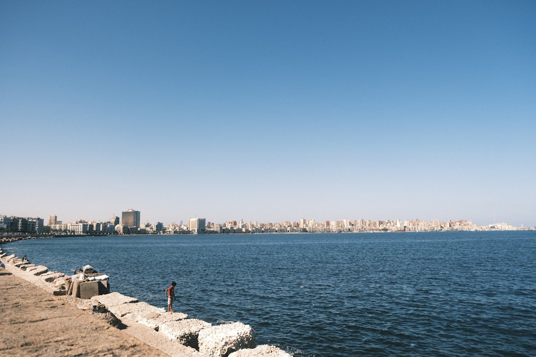 City skyline along the ocean with a man fishing