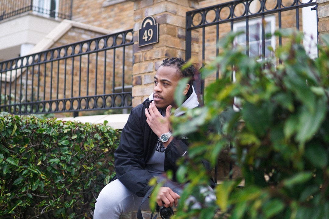 man in black jacket sitting on green plant during daytime