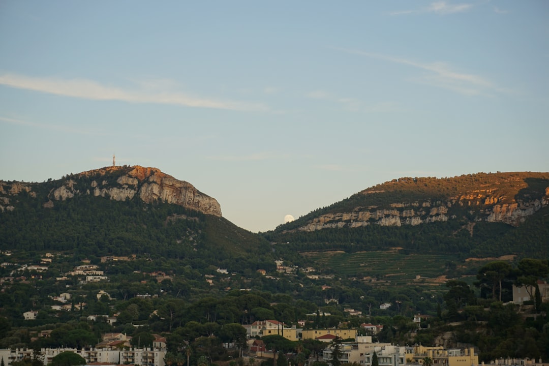 Green hills with buildings at the base under sky.