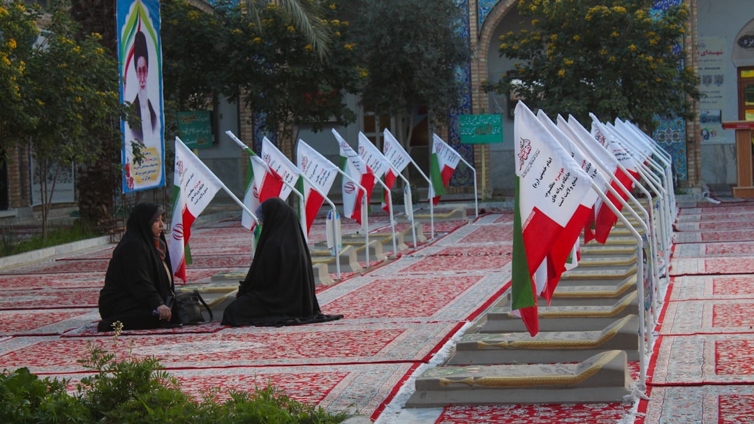 A group of people sitting on the ground in front of flags