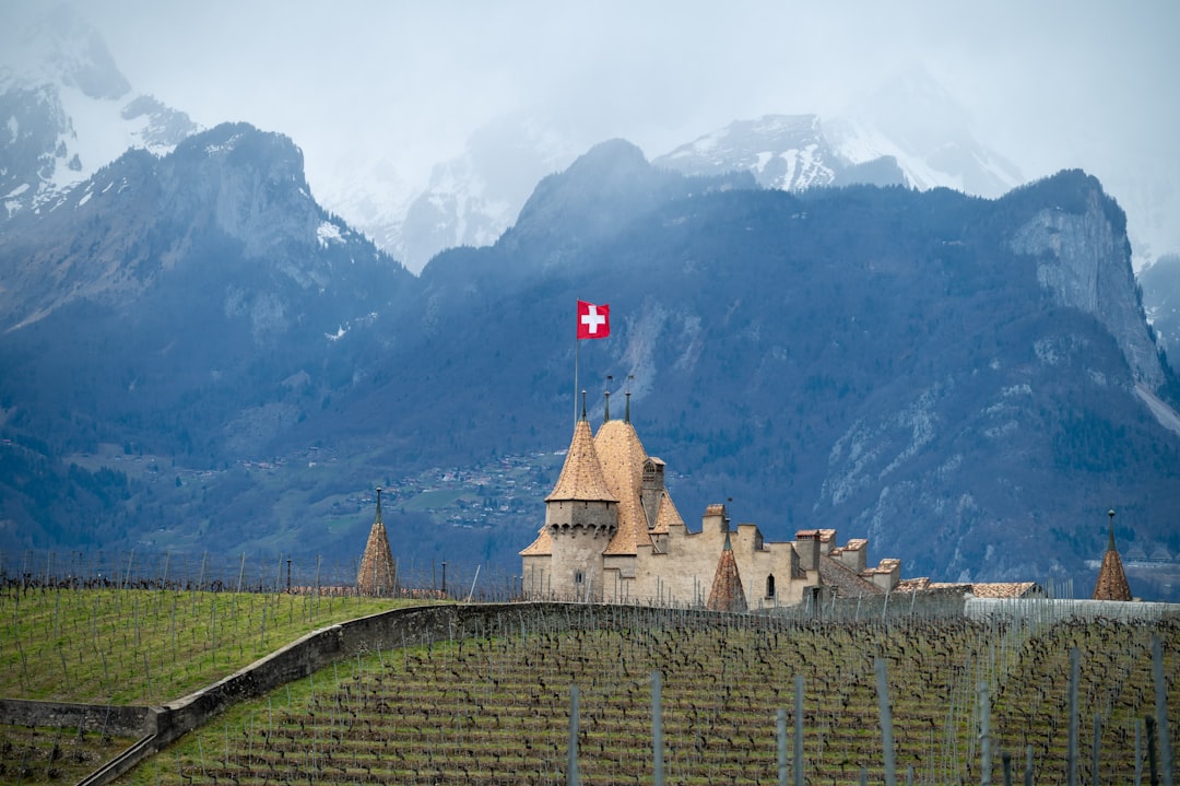 Castle with swiss flag in front of snowy mountains