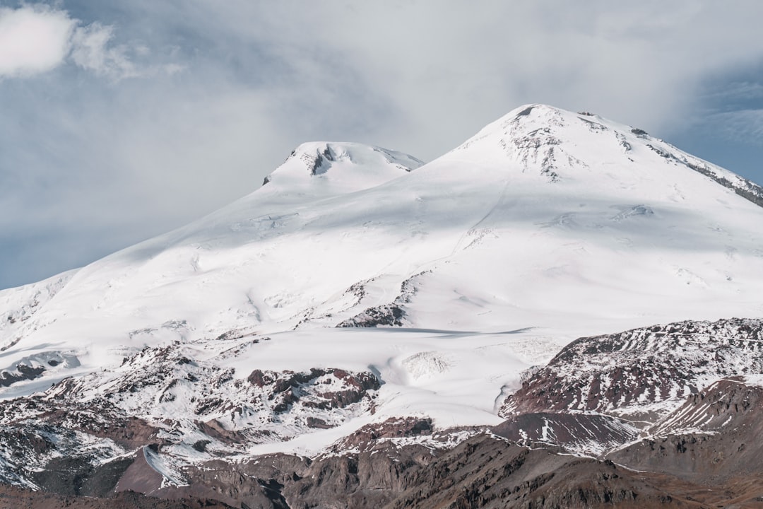 a mountain covered in snow under a cloudy sky