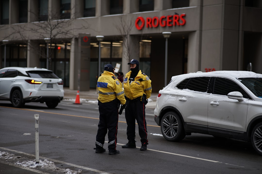 2 men in yellow jacket standing beside white car during daytime