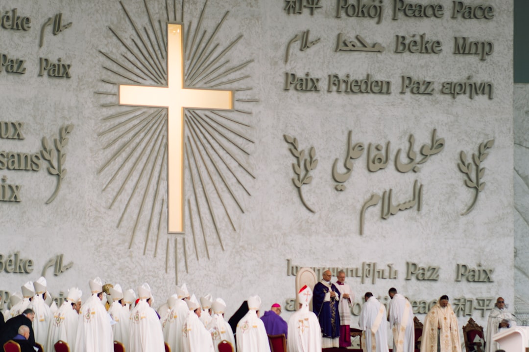 A large cross on a wall with people gathered below.