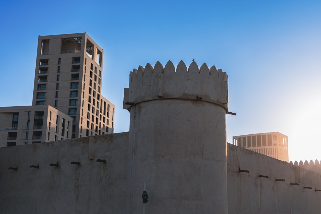 Old fort wall with modern buildings behind it.