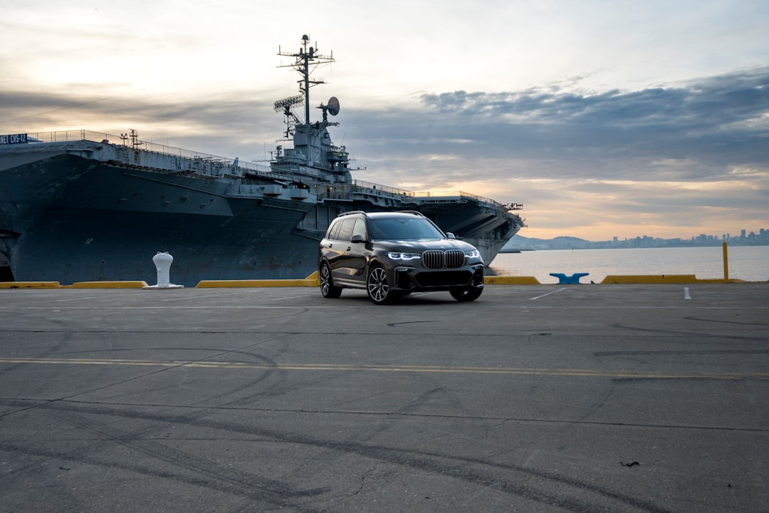 Suv parks in front of a large warship.