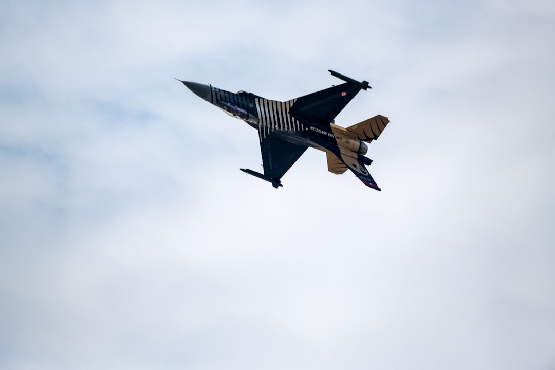 A fighter jet performs a maneuver against a cloudy sky.