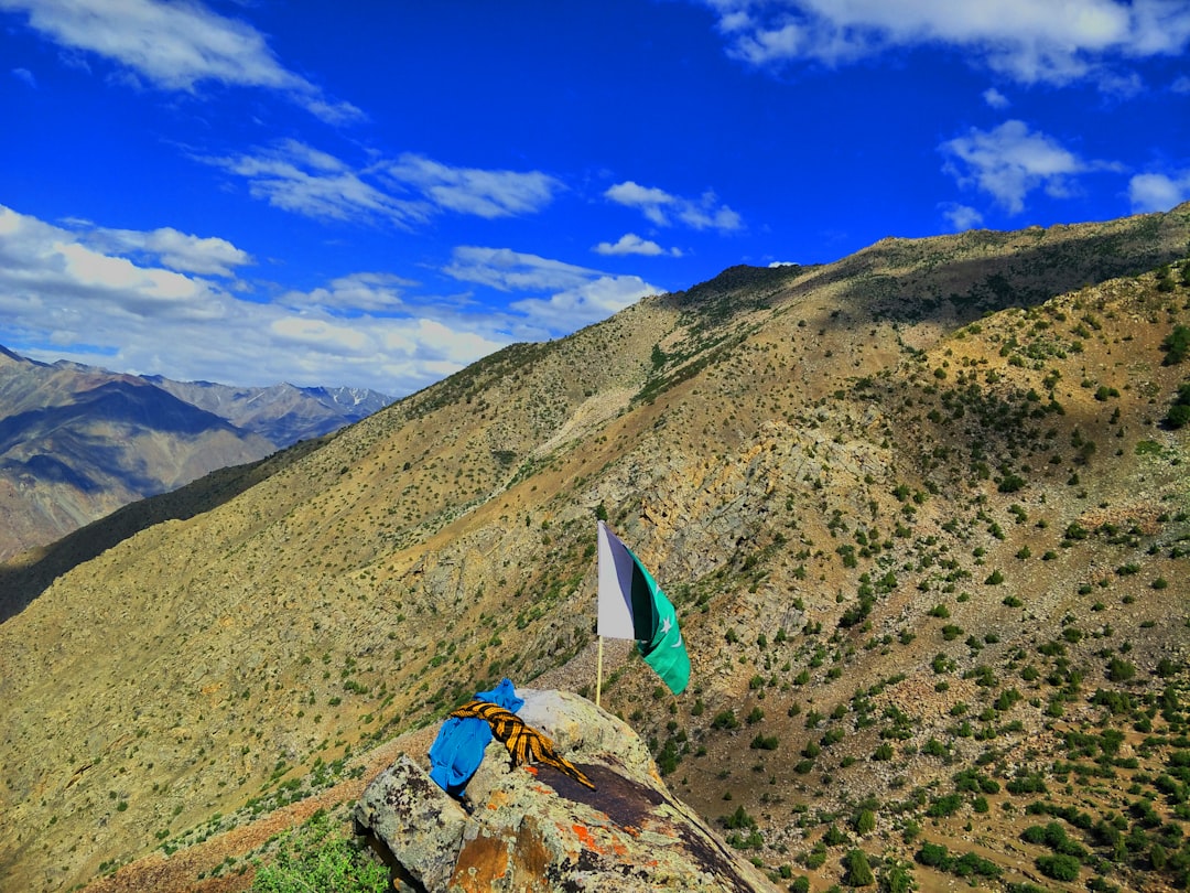 white sailboat on green grass field near mountain under blue sky during daytime