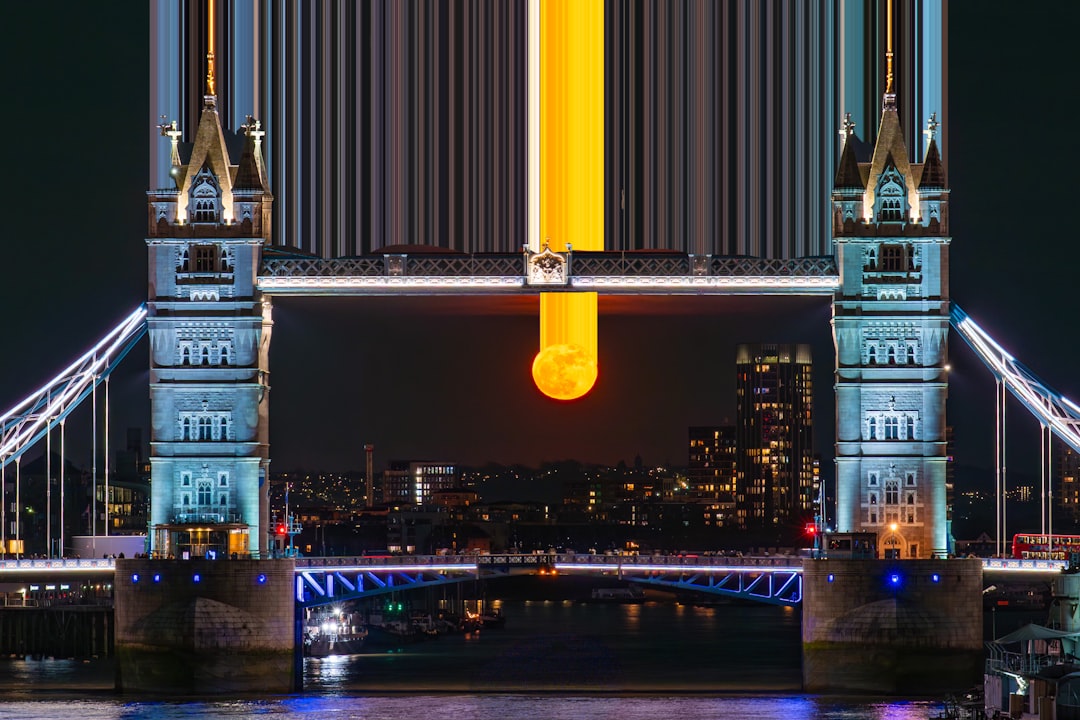 Orange moon perfectly framed by london's tower bridge at night.