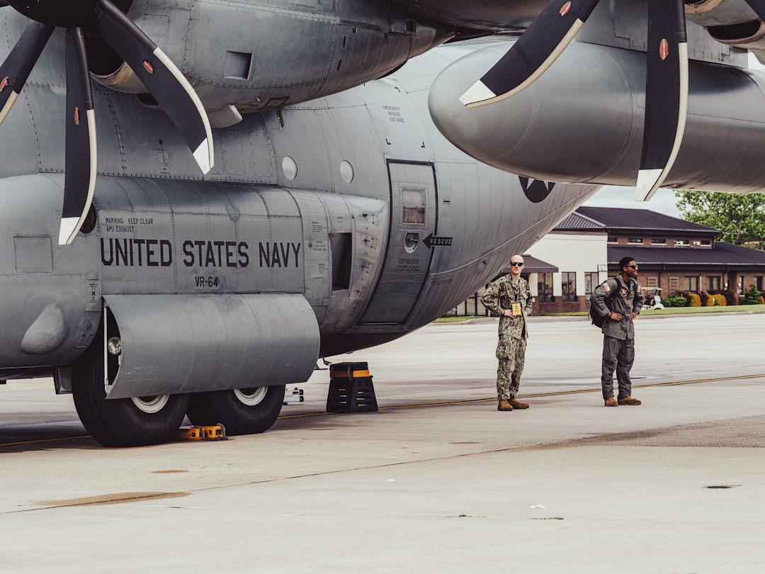 Two navy personnel stand by a military aircraft
