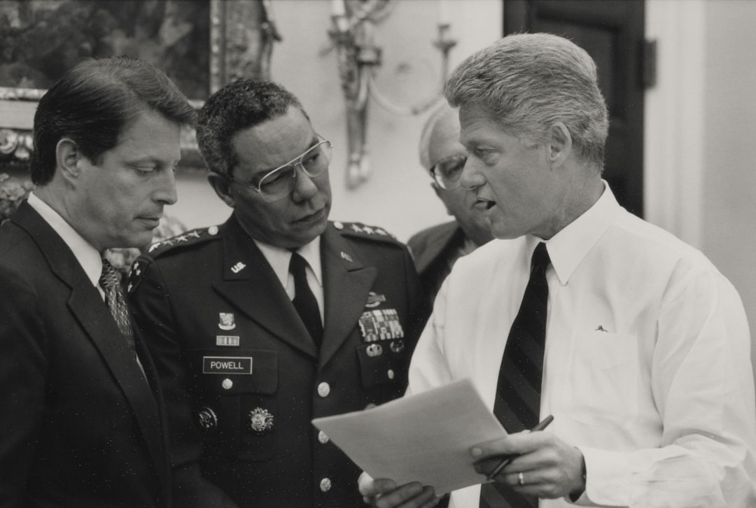 Three men in formal attire discussing documents