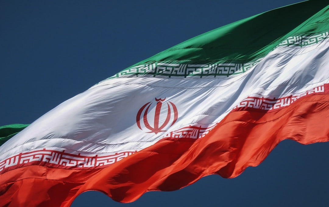 The flag of Iran waving against a clear dark blue sky
