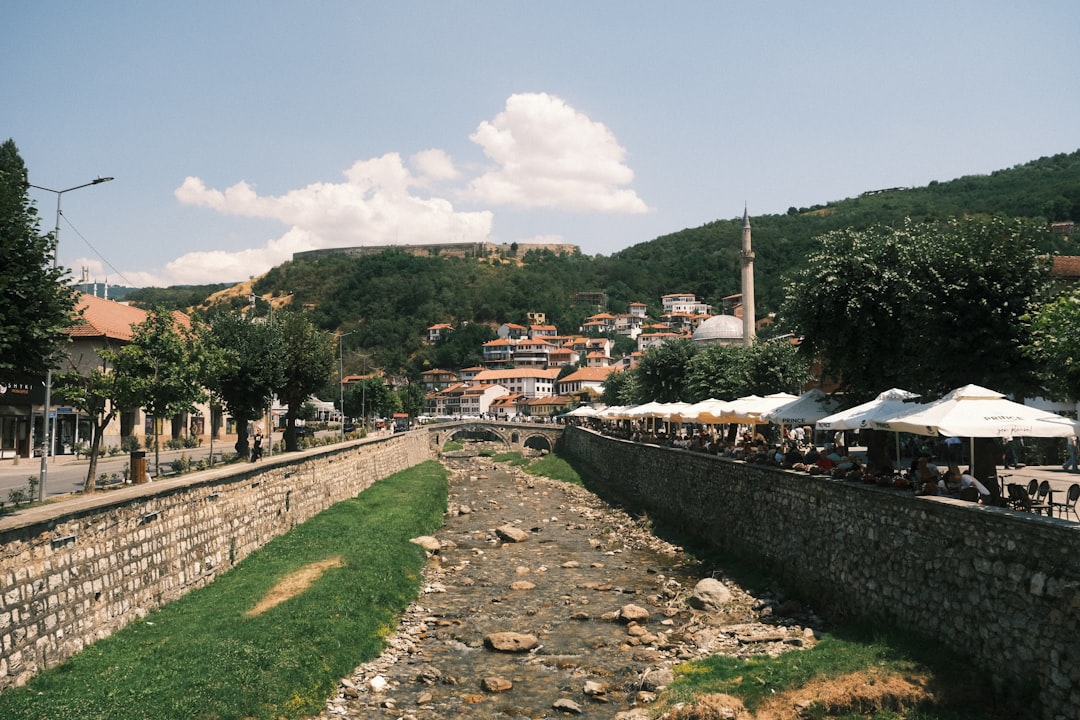 A dry riverbed runs through a town with hills behind