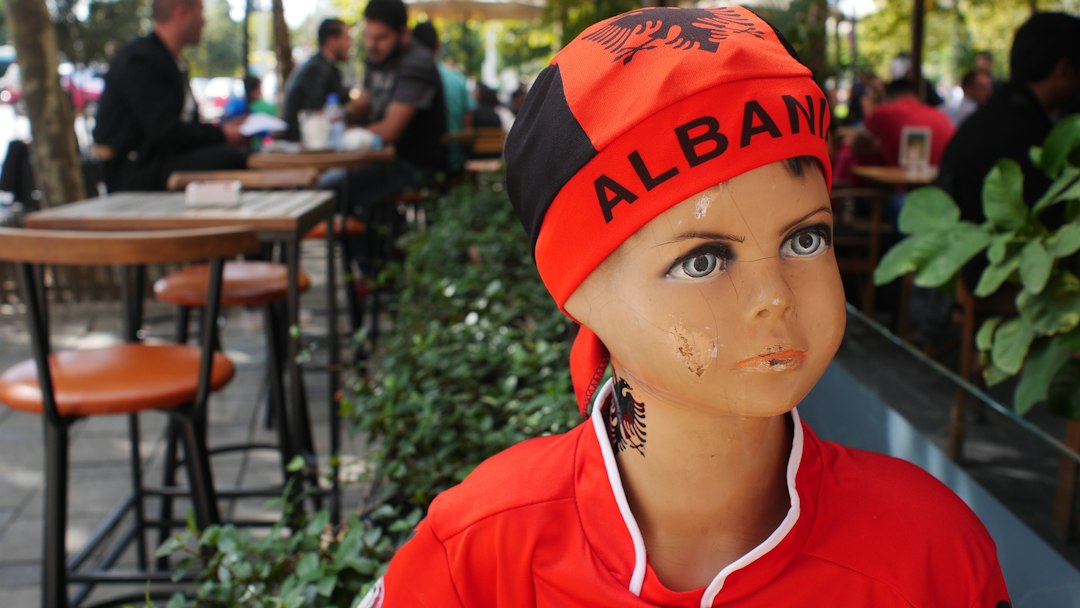 A child mannequin wearing an albania bandana outside a cafe