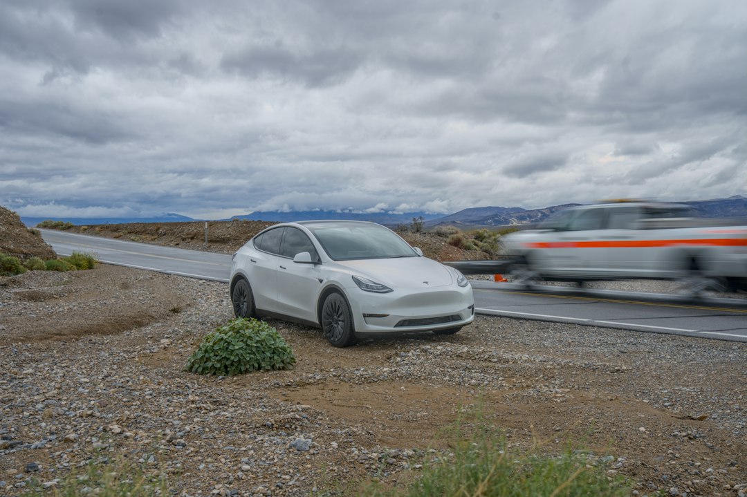 White car parked on a gravel roadside under cloudy sky