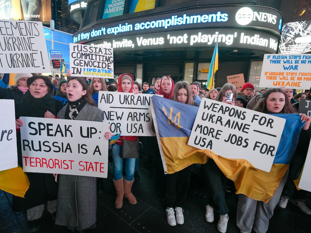 A group of people holding protest signs and a Ukrainian flag in Times Square